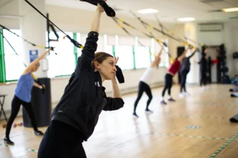 People exercising with suspension trainers in a fitness class.