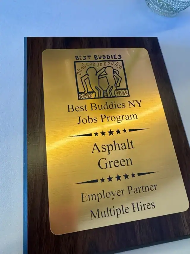 A wooden plaque awarded to Asphalt Green by Best Buddies NY Jobs Program, recognizing them as an employer partner with multiple hires.