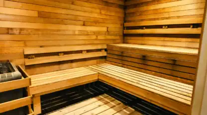 Interior of a wooden sauna with tiered bench seating and a heater in the corner. Walls, ceiling, and benches are all constructed from horizontal wooden planks.