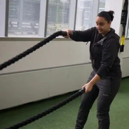 An Asphalt Green Fitness trainer performs the altnernating battle ropes waves. 