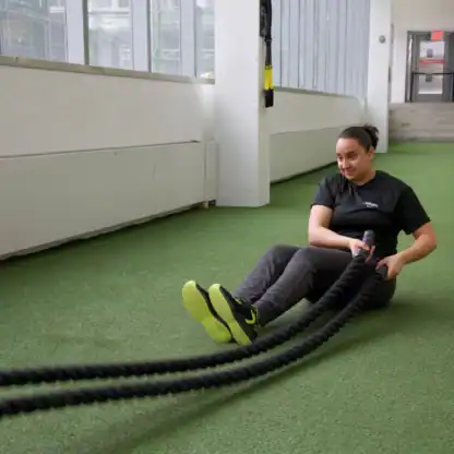 An Asphalt Green Fitness trainer performs the battle ropes Russian twists exercise to improve core strength. 