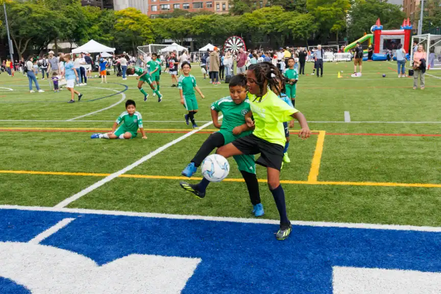 Two kids participate in a drill at Big Kick, Asphalt Green's free community soccer festival.