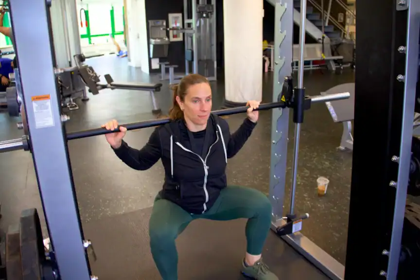 An Asphalt Green Fitness trainer performs the Smith machine squat.