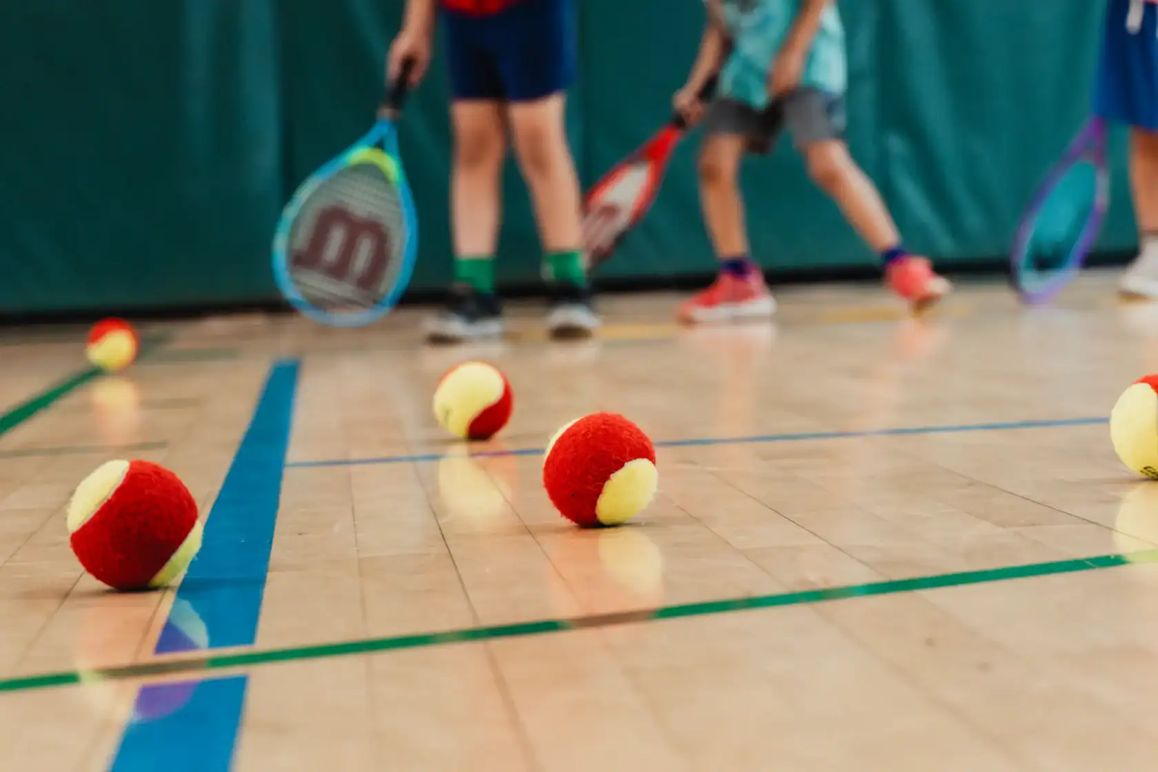 Three kids holding tennis rackets during an Asphalt Green youth tennis class