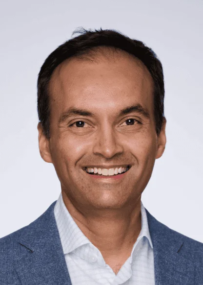 Headshot of a smiling man wearing a blue blazer and a light-colored button-down shirt.