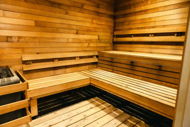 Interior of a wooden sauna with tiered bench seating and a heater.