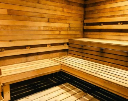 Interior of a wooden sauna with tiered bench seating and a heater.