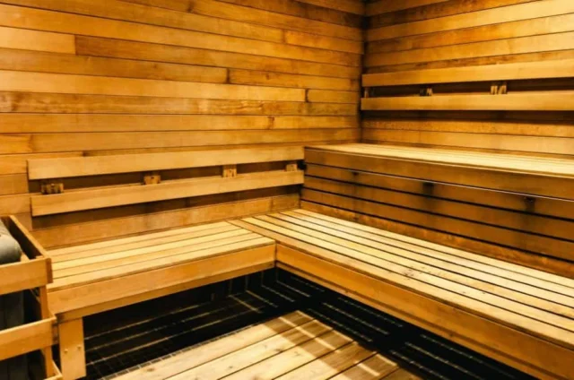 Interior of a wooden sauna with tiered bench seating and a heater.
